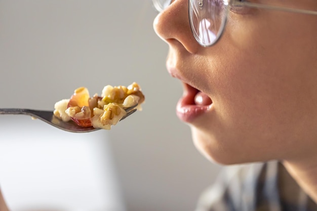 Una niña come gachas con frutas en primer plano.