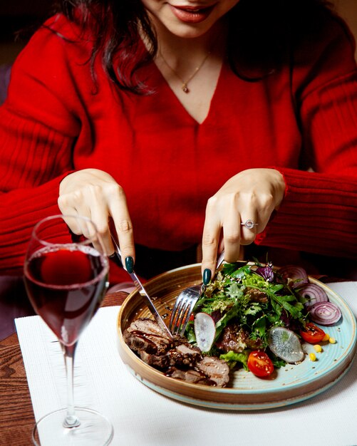 Niña comiendo ensalada de carne con cebolla