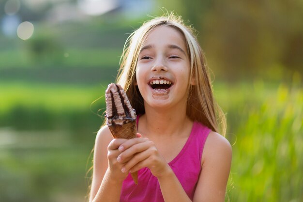 Niña comiendo helado de chocolate en el parque