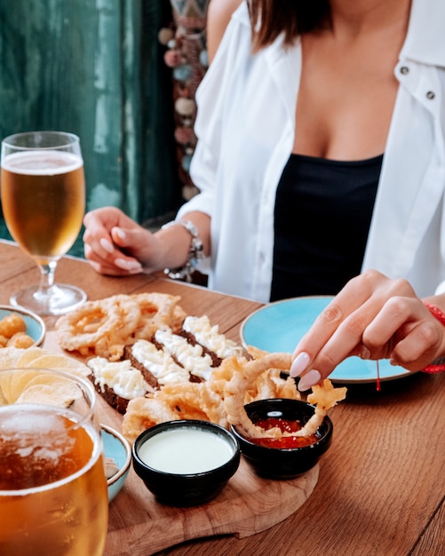 Niña comiendo un set de cerveza y bebiendo cerveza con espuma