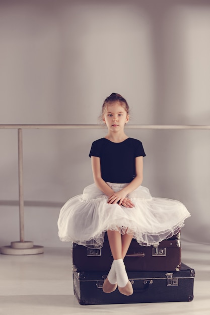 La niña como bailarina de balerina sentada en el estudio