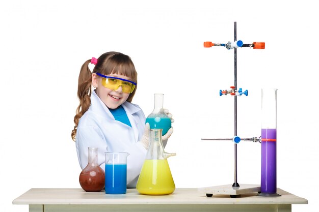 Niña como químico haciendo experimento con fluido químico en el laboratorio