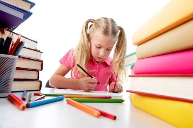 Niña concentrada rodeada de libros de colores