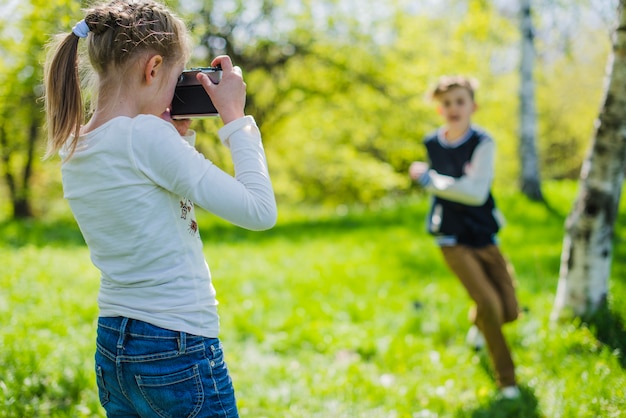 Foto gratuita niña concentrada usando su cámara al aire libre