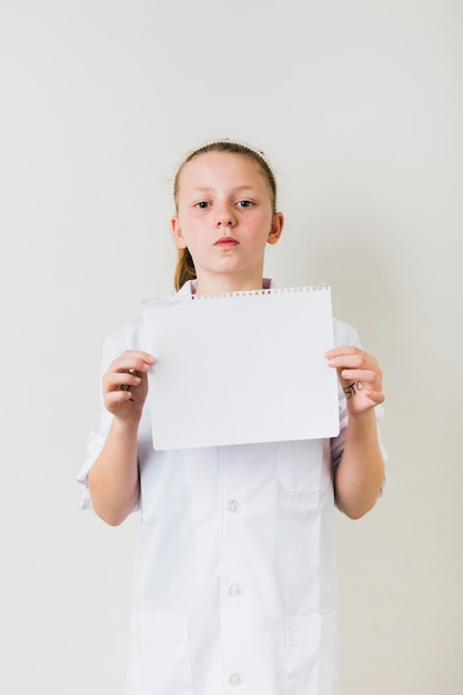 Niña confiada que sostiene la hoja de papel vacía