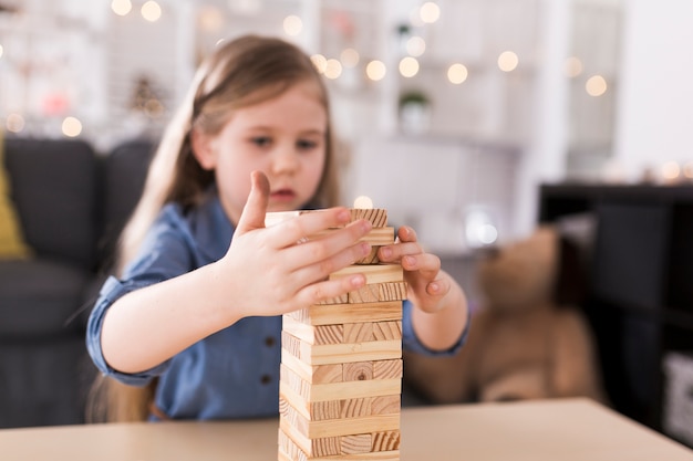 Niña construyendo torre de ladrillos de madera