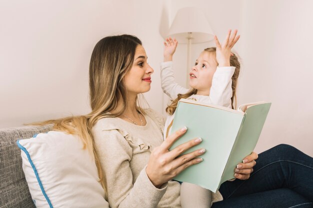 Niña contando historia a mamá mientras lee un libro