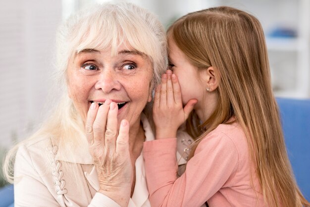 Niña contando secretos a la abuela