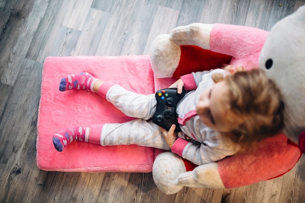 Niña con controlador en sillón