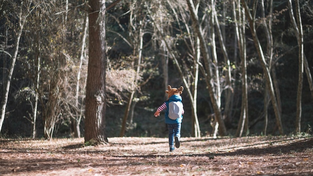 Niña corriendo en el bosque soleado