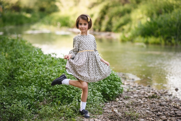 Niña en la corriente de la naturaleza con un vestido hermoso