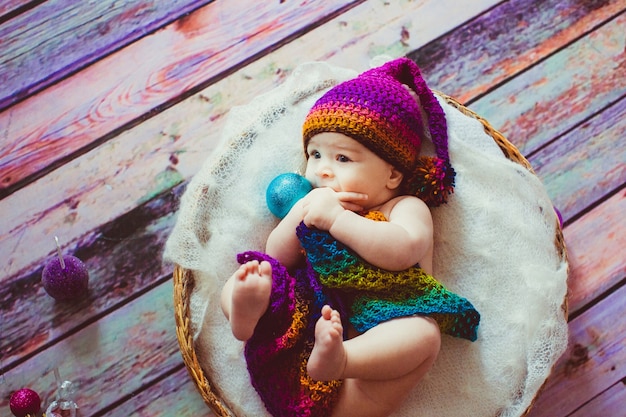 Foto gratuita la niña cubierta con la manta colorida miente en la almohada suave en la cesta