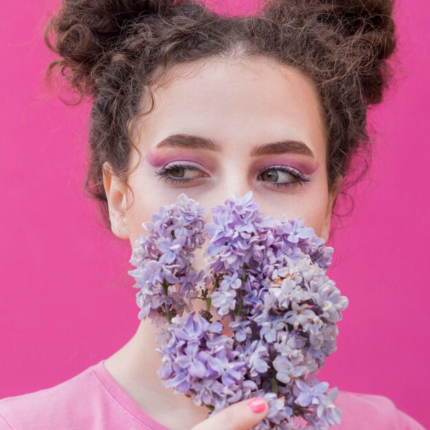 Niña cubriéndose la cara con flores lilas