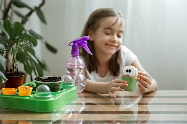 Una niña cuida un juguete con el que crece la hierba.