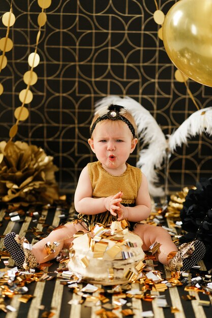 Niña curiosa asomando el dedo en su primer aplastamiento de pastel de cumpleaños.