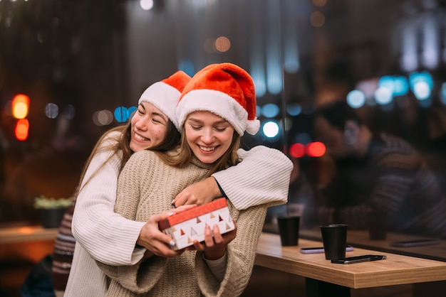 La niña le da un regalo a su amiga en caffe