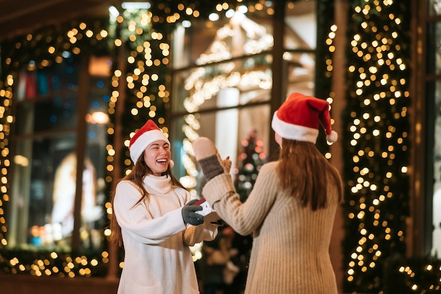 La niña le da un regalo a su amiga en la calle. Retrato de felices lindos jóvenes amigos