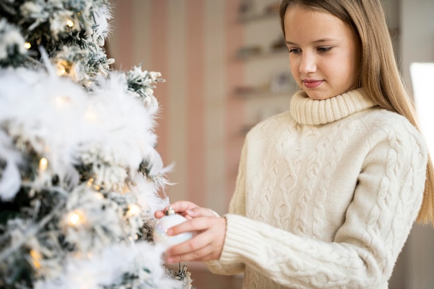 Foto gratuita niña decorando el árbol de navidad