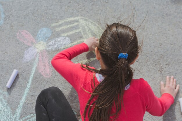 Niña dibujando con tiza en calle