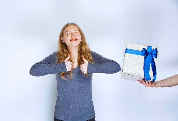 La niña disfruta de la caja de regalo azul blanca que se le ofrece.