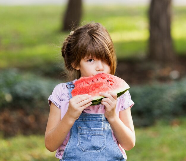 Niña disfrutando de rodaja de sandía afuera