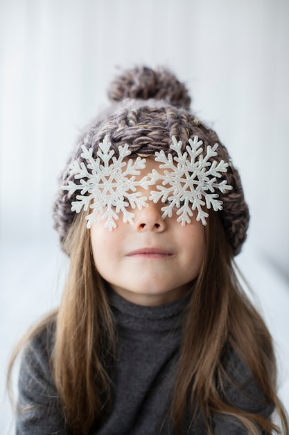 Niña divertida con copos de nieve como ojos