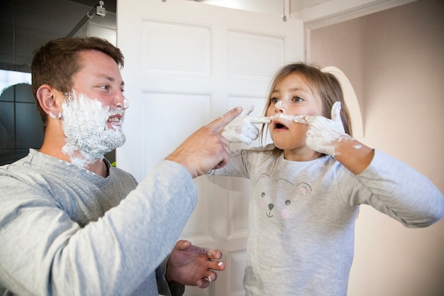 Niña divertida pintándose un bigote con espuma de afeitar