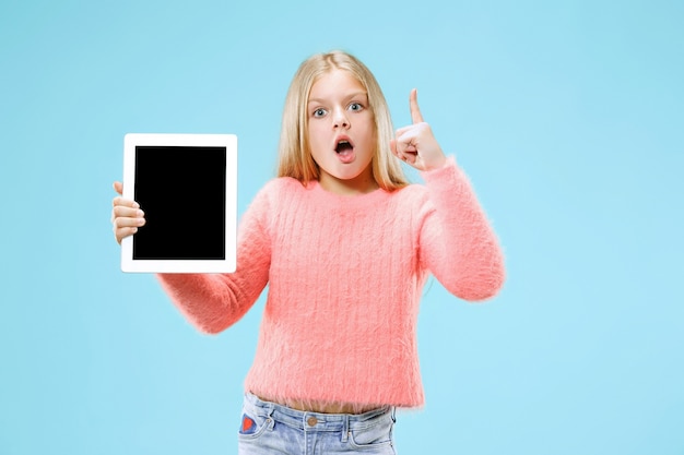 Niña divertida con tableta en estudio azul.