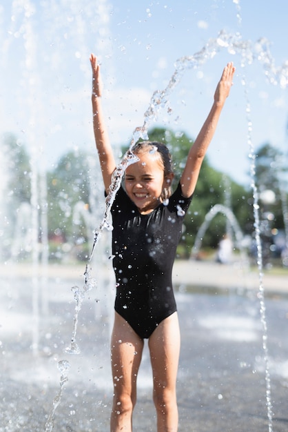 Niña divirtiéndose en la fuente de agua