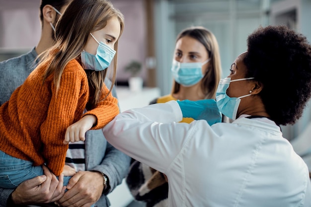 Niña y doctora afroamericana golpeando el codo en la clínica médica