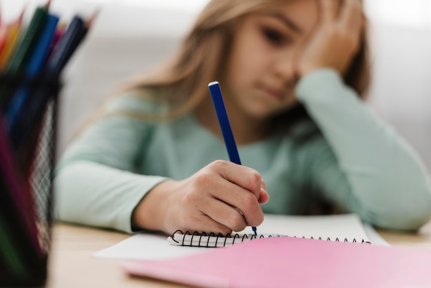 Foto gratuita niña con dolor de cabeza mientras hace sus deberes