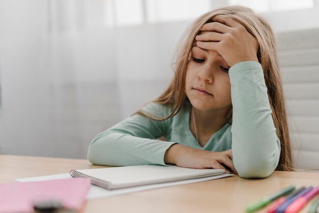 Niña con dolor de cabeza mientras realiza clases en línea