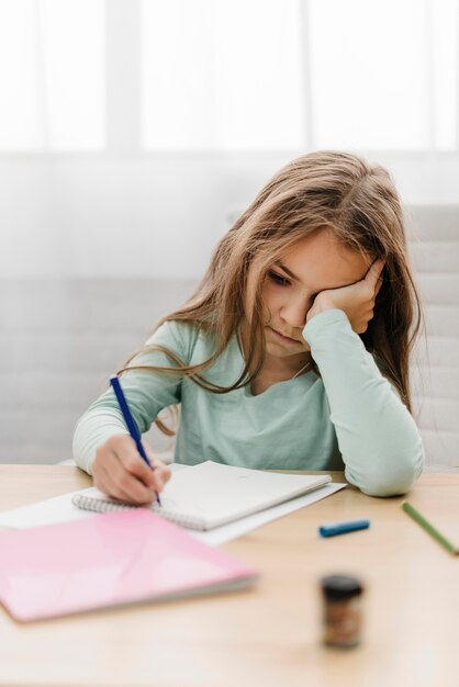 Niña con dolor de cabeza mientras realiza clases en línea