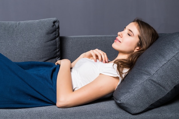 Niña durmiendo en un sofá cubierto con colcha azul sobre fondo gris