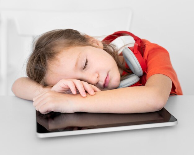 Niña durmiendo en tableta mientras usa auriculares