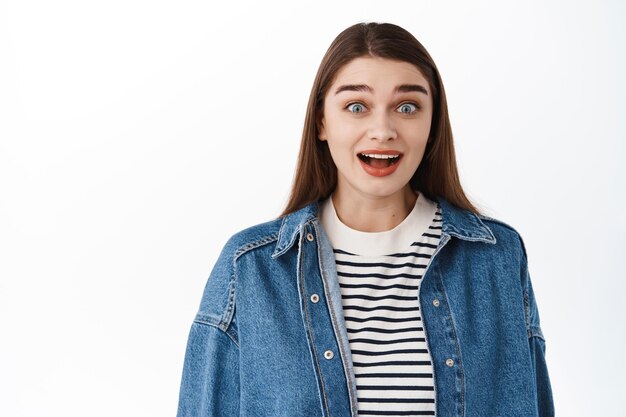 Niña emocionada sorprendida jadeando, mirando con asombro con cara feliz sorprendida, escuchar buenas noticias asombrosas, regocijo, de pie contra el fondo blanco sin palabras