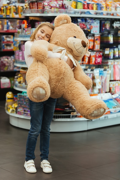 Foto gratuita niña encantada con gran oso de peluche