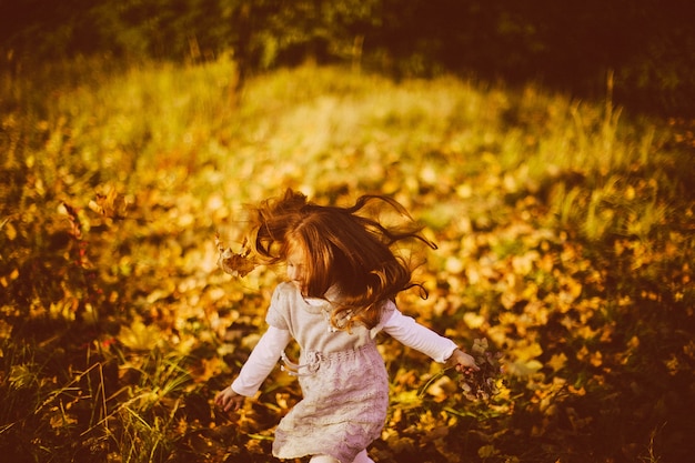 Niña encantadora corre en hierba alta de otoño