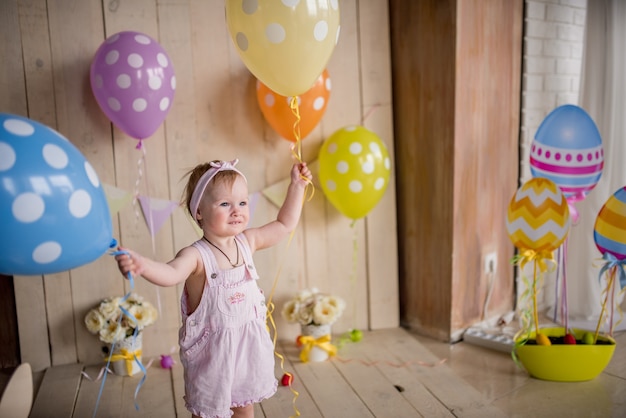 Niña encantadora se ve feliz jugando con globos de colores