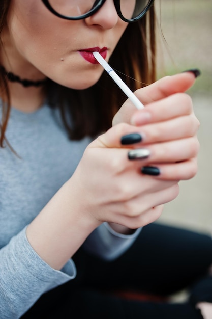 Niña encendiendo cigarrillos al aire libre de cerca Concepto de adicción a la nicotina por adolescentes