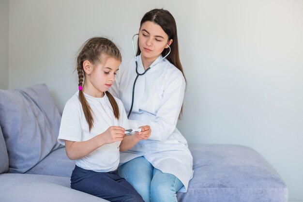 Niña enferma siendo examinada por la doctora