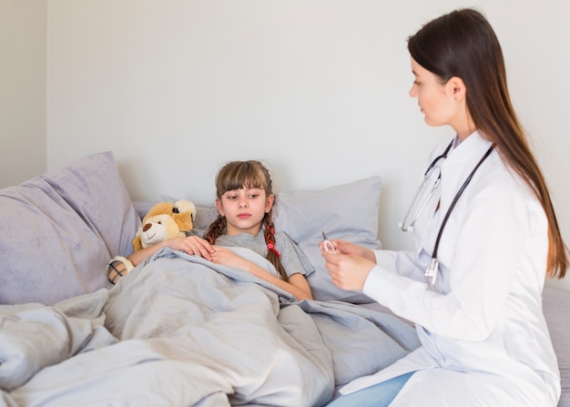 Niña enferma siendo examinada por la doctora