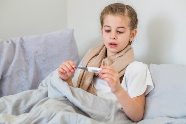 Niña enferma usando el termómetro