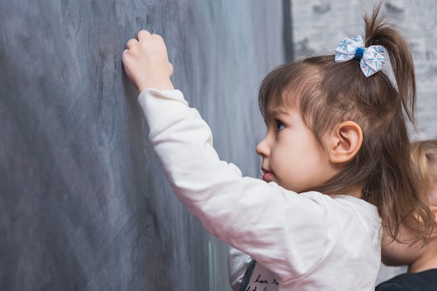 Niña enfocada escribiendo en la pizarra