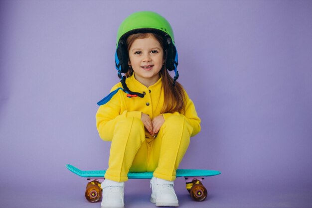 Niña enseñando a andar en monopatín con casco