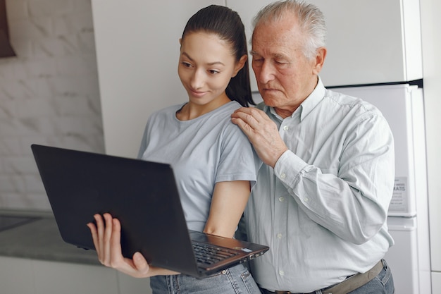 Niña enseñando a su abuelo a usar una computadora portátil