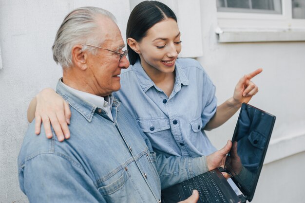 Niña enseñando a su abuelo a usar una computadora portátil