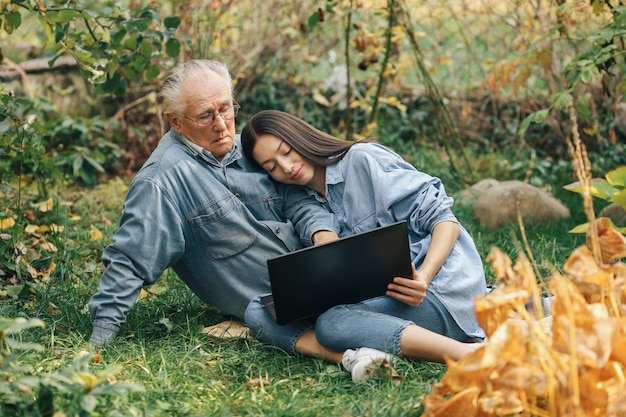 Niña enseñando a su abuelo a usar una computadora portátil