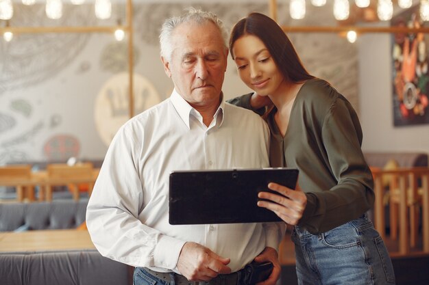 Niña enseñando a su abuelo a usar una tableta
