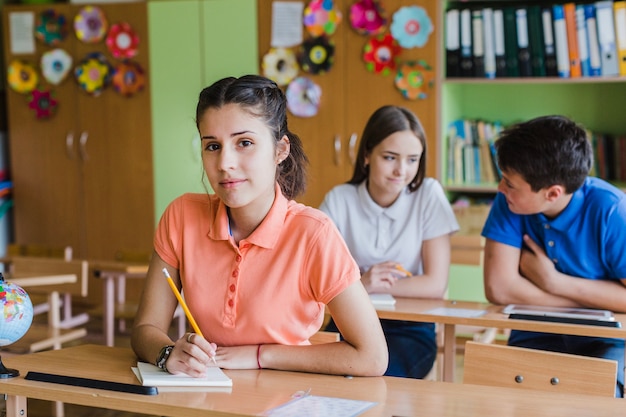 Niña escribiendo y posando en el colegio